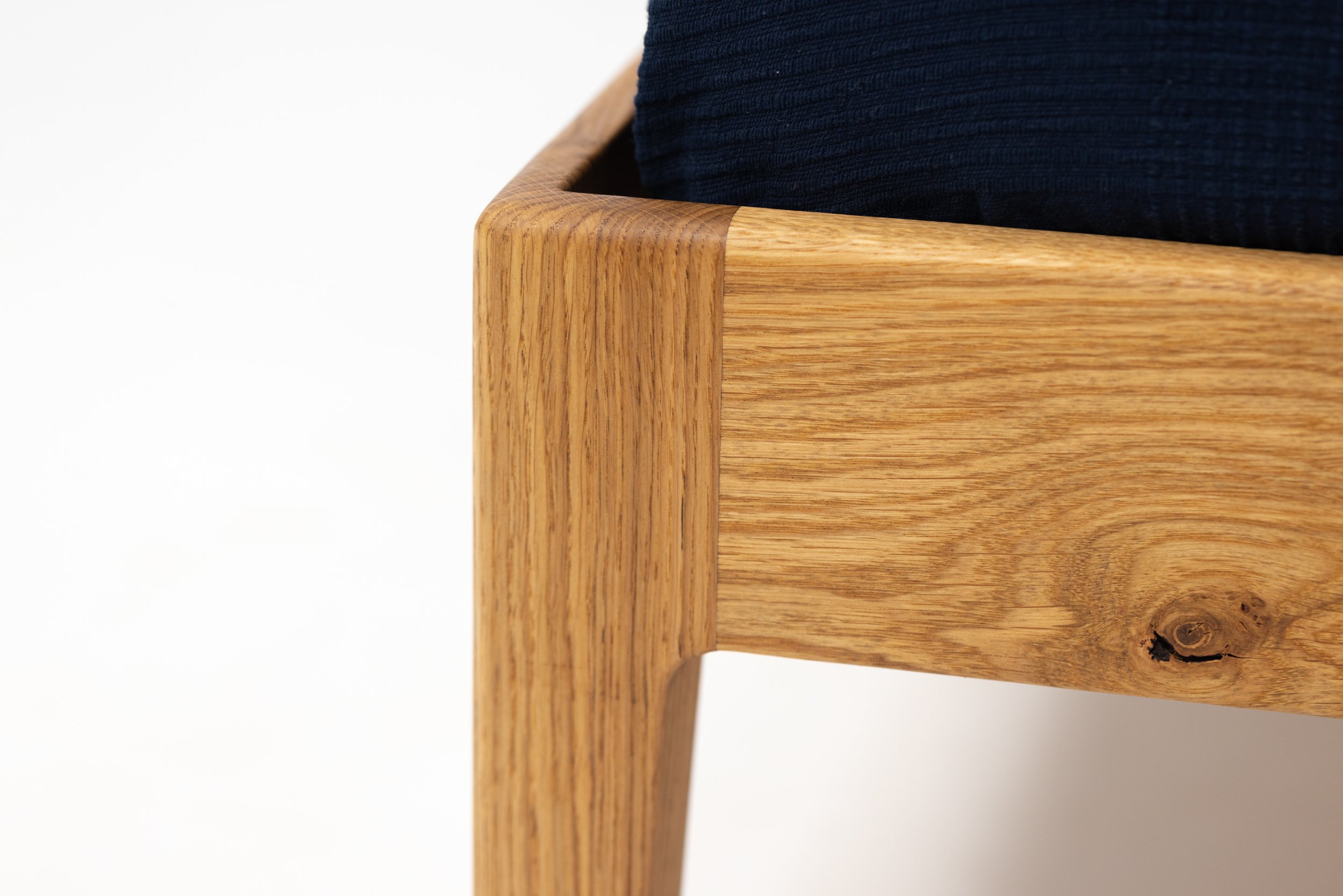 Nahaufnahme eines Holzstuhls mit einer schwarzen Sitzfläche.