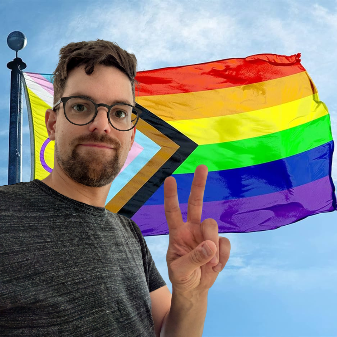 Mann mit Brille macht Peace-Zeichen vor Regenbogen-Flagge der LGBTQ+ Community, im Hintergrund ist eine südafrikanische Flagge zu sehen.