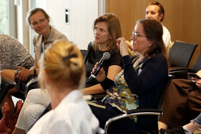 Fünf Frauen bei einer Diskussion oder Fragerunde in einem Konferenzraum, eine Frau spricht mit einem Mikrofon.