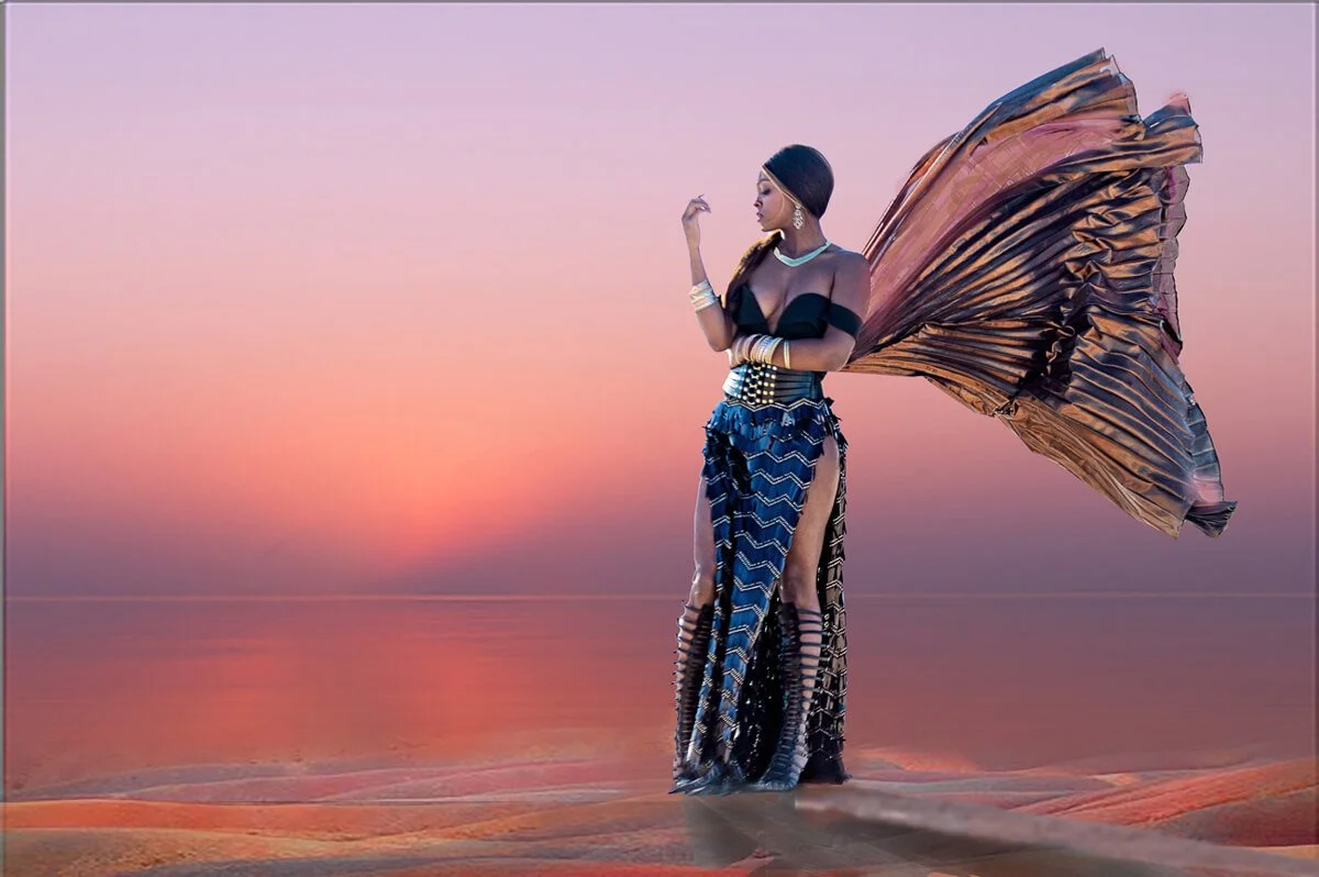 A striking silhouette stands poised at the edge of a quiet beach, framed by the dreamy transition of day into night. The sky is an opalescent tapestry of soft purples, pinks, and fading golds—sunset at its most poetic. Watery sand stretches in both d