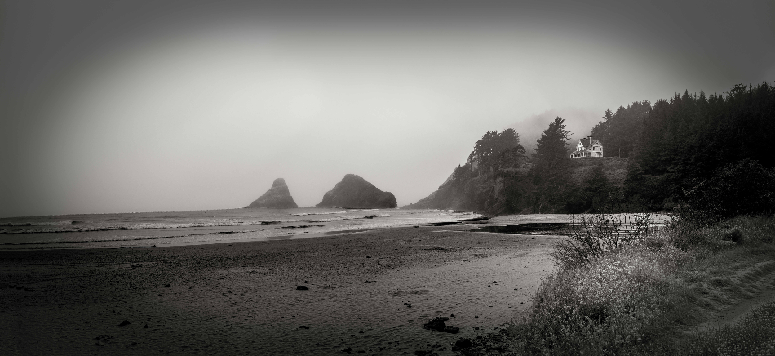 Mist drifts along the quiet shore, waves thunder against forgotten stone. A lone house watches from the cliff; home for the keeper of tides, guardian of fog. Here, the world softens into silence.