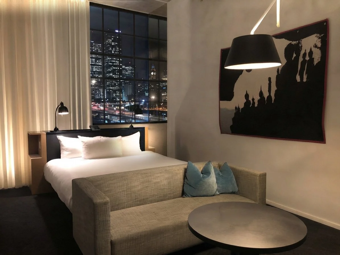 Guest room at 21c Oklahoma City with decorative pendant lighting, seating area and large industrial window.
