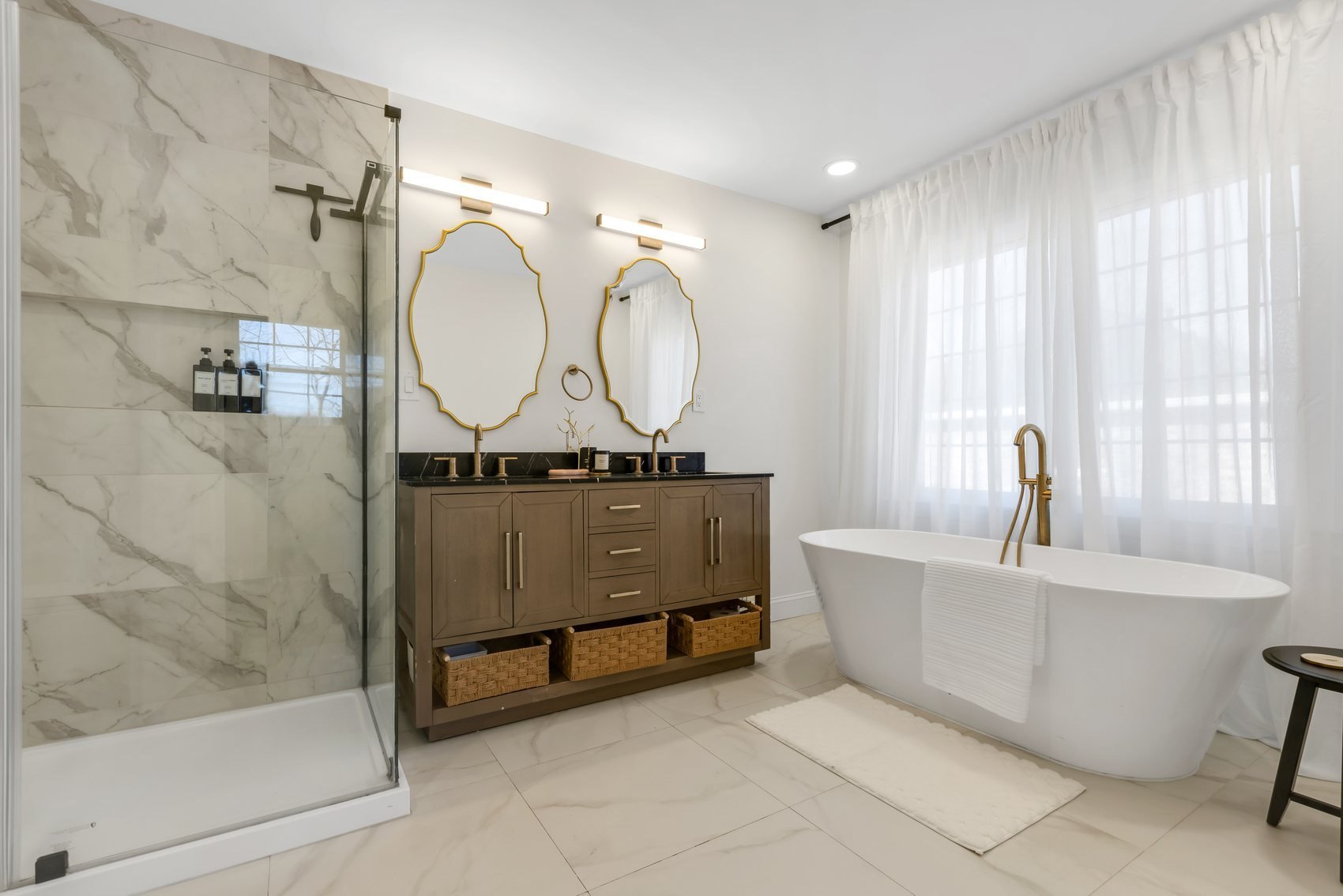 Primary bathroom with full height marble shower and gold framed oval mirrors, Roswell GA