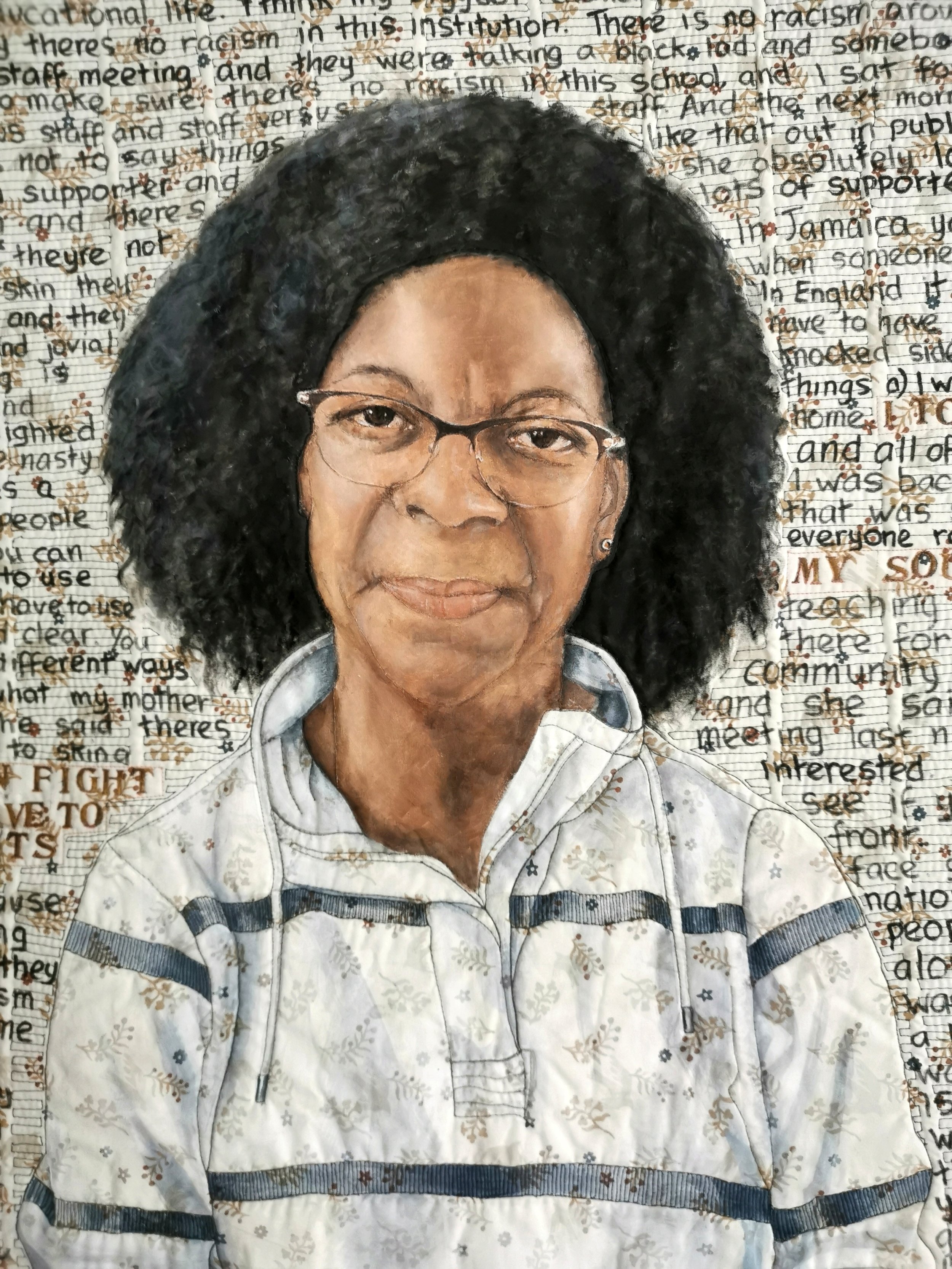 Portrait of a person with glasses and curly hair, wearing a patterned shirt, with a background of densely written text.
