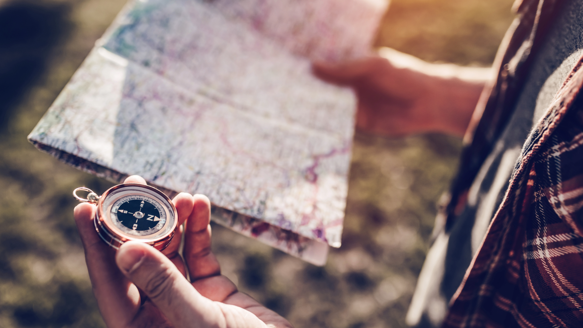 person looking at map while holding compass