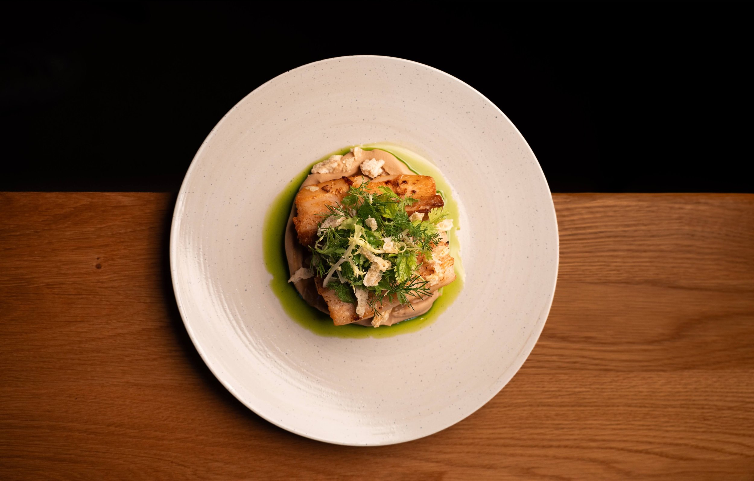 Overhead view of pork belly with vegetable rissolés and jus at NERI in Zürich