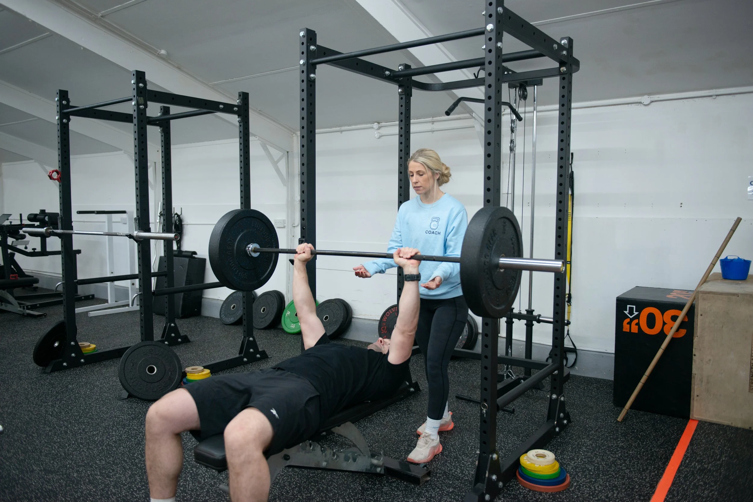 A row of dumbbells and kettlebells arranged on a rack in a gym.