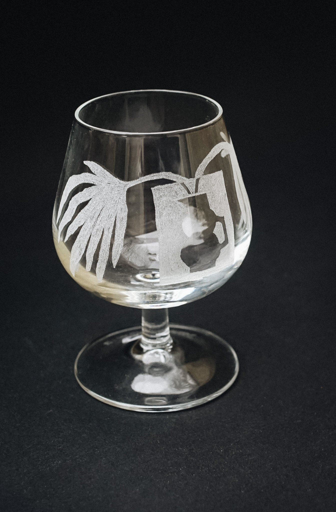 Verre à pied transparent décoré de motifs gravés.
