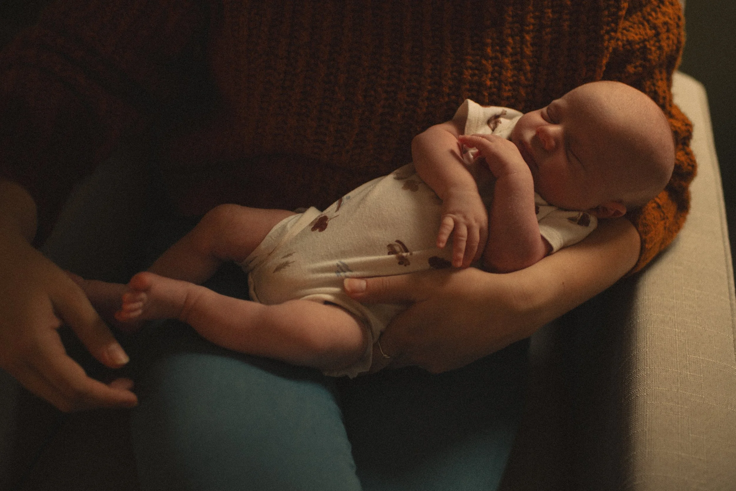 A newborn baby sleeping peacefully while being held in someone's arms