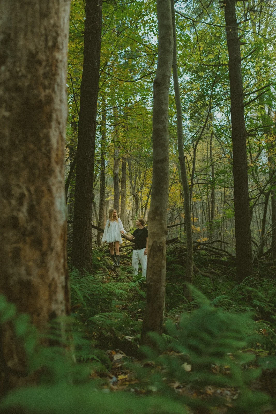 Couple adventuring in the woods with tall trees