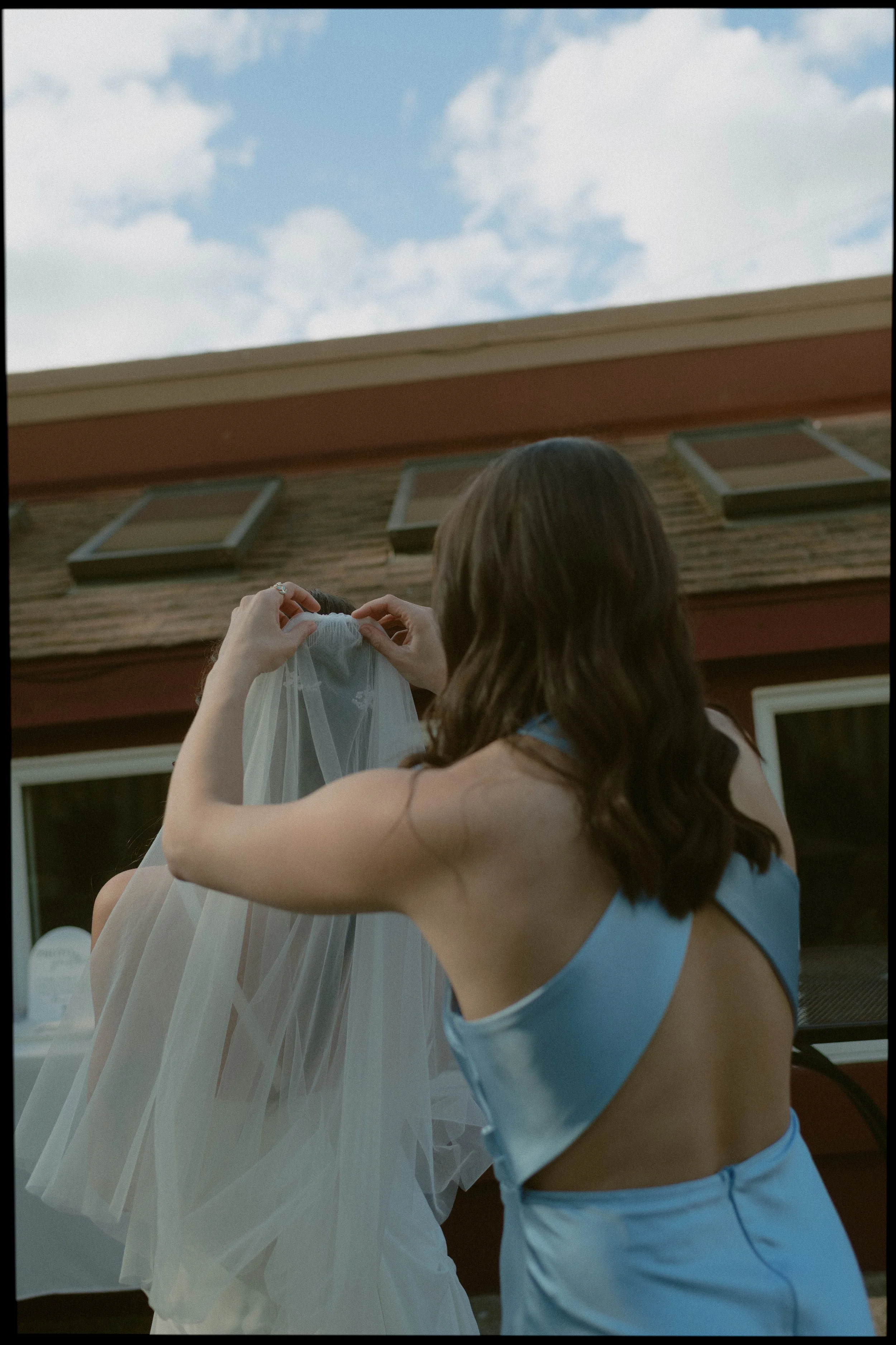 Maid of honor helping with the brides veil at wedding