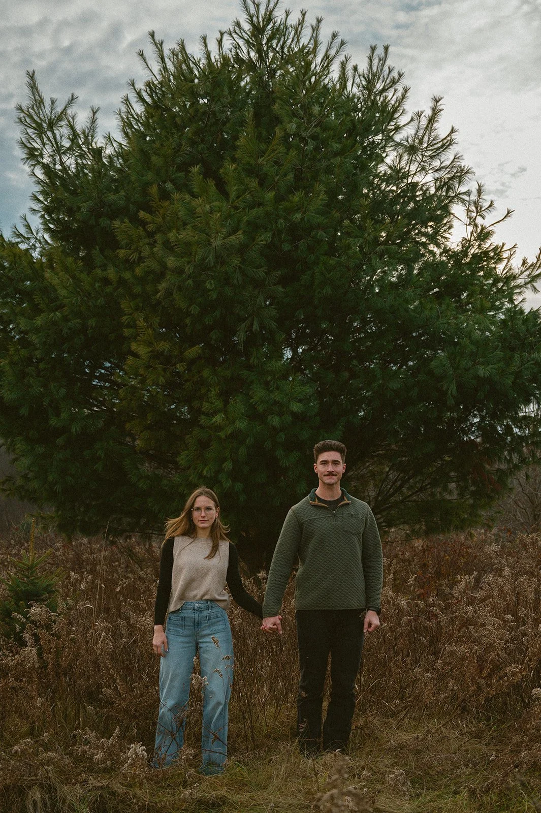 Couple on their property holding hands in front of a tree