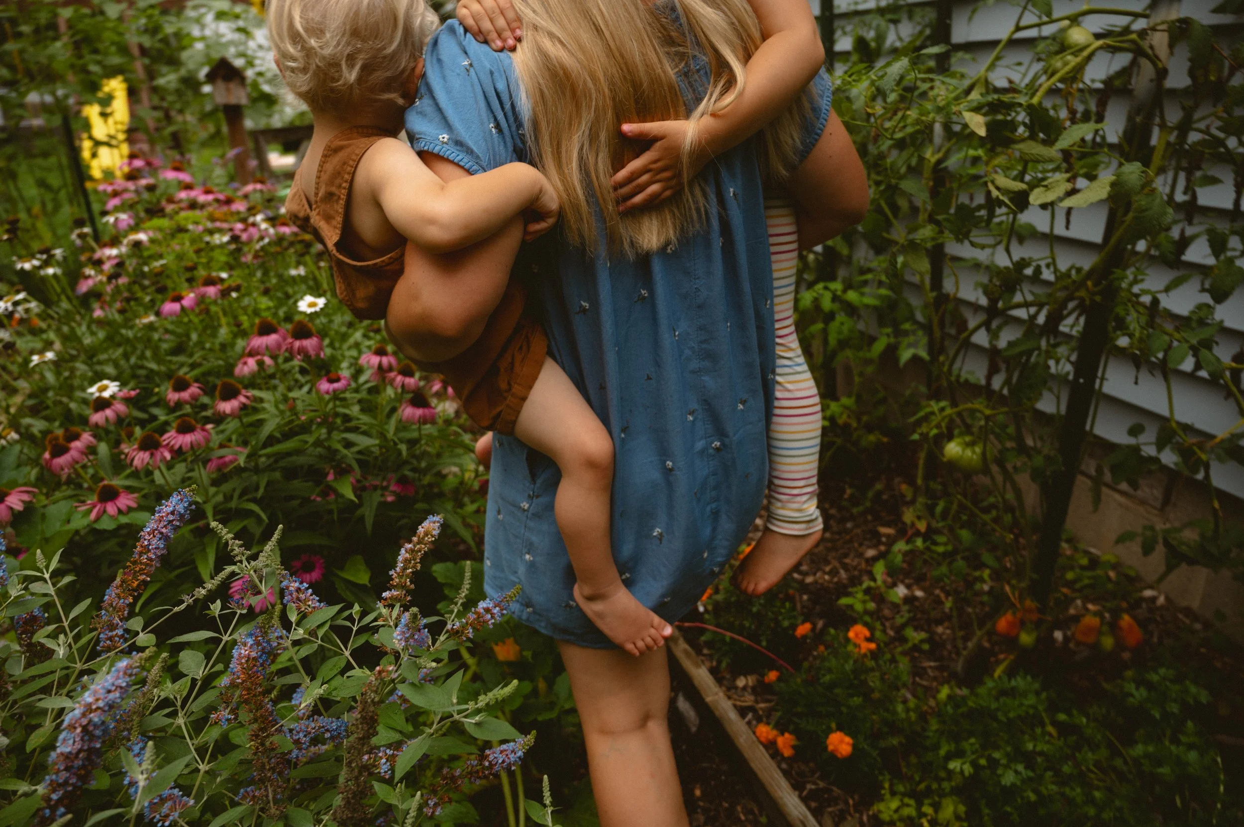 Momma carrying her two kids through their garden