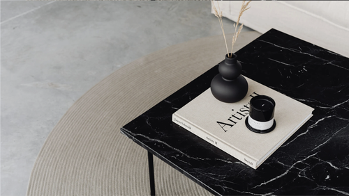 Black marble side table with a candle and books in the CoCo lounge — view more on Instagram
