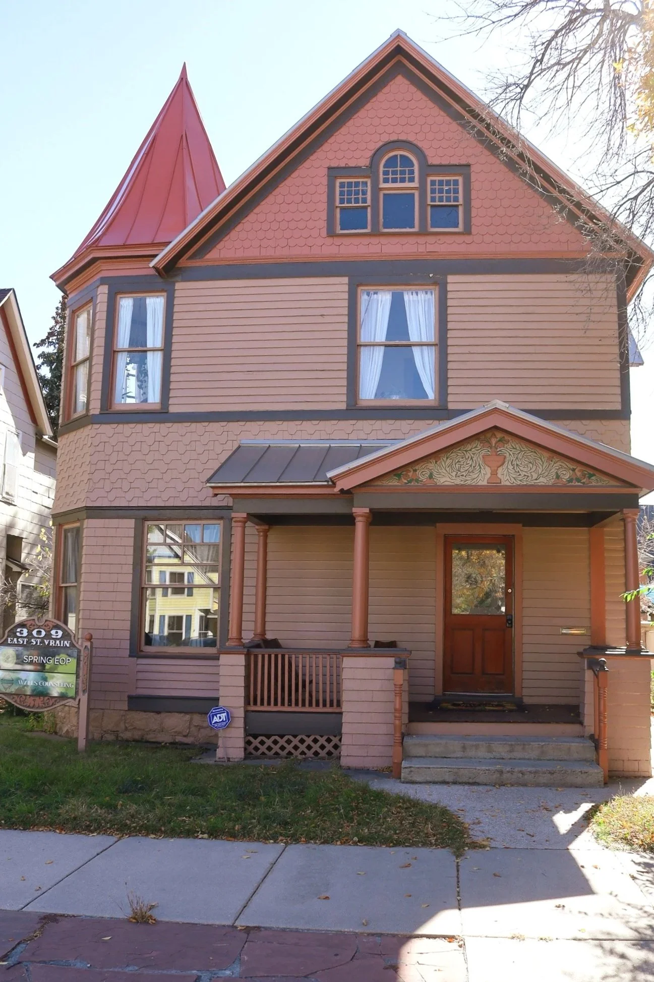 Exterior of Walls Counseling building in Colorado Springs, a three-story pink Victorian-style house with turret, arched windows, and welcoming front porch, home to therapy and counseling services.