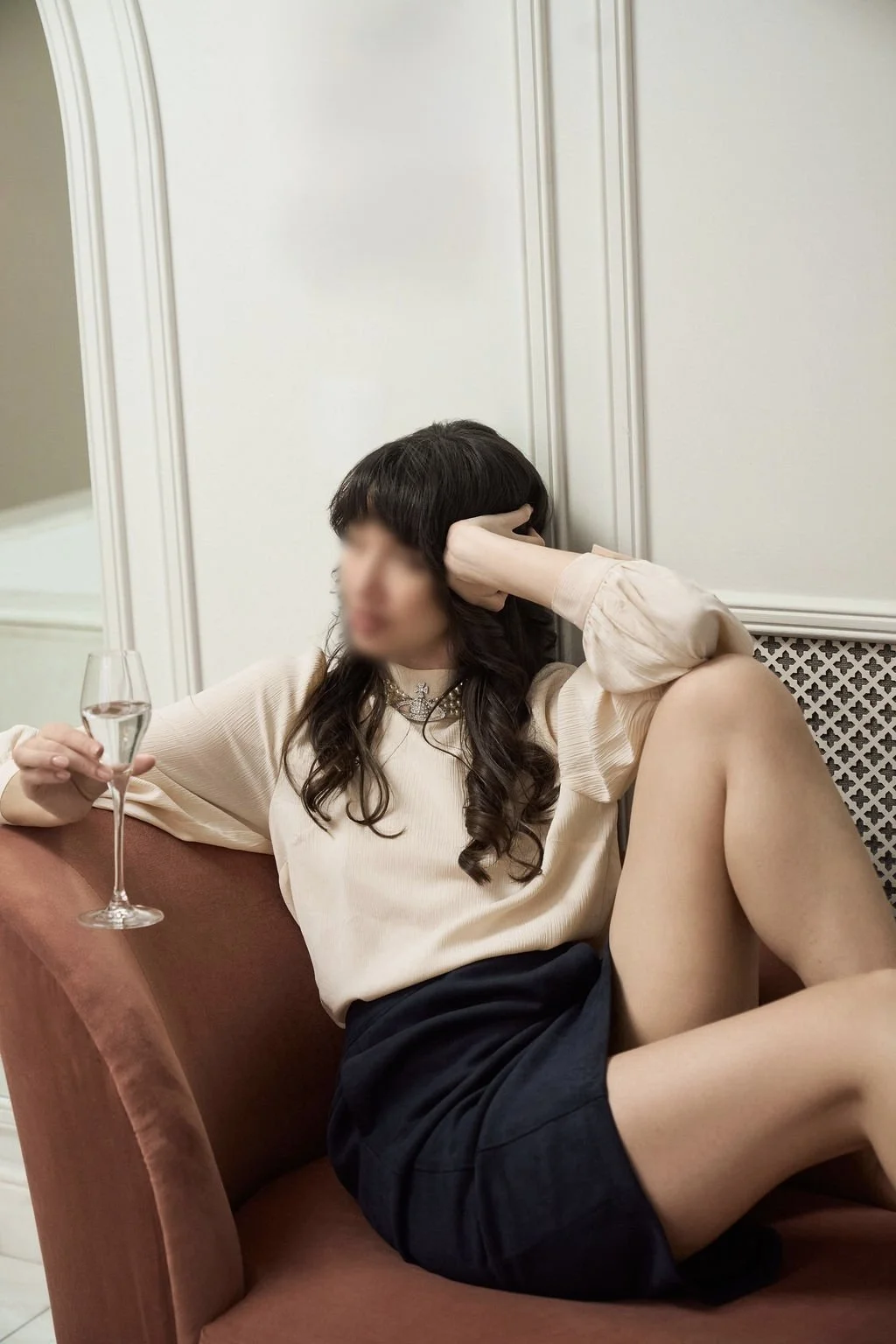 Charlie Levine lounging on a sofa in a white top and a blue skirt