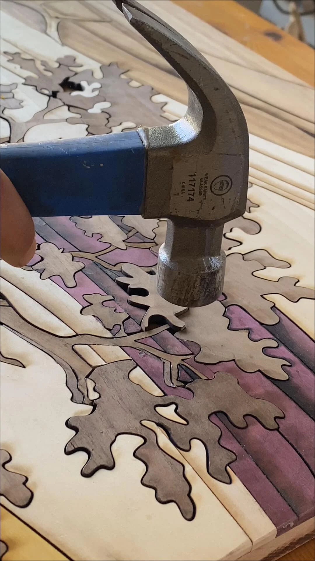 A tool pressing a wooden puzzle piece, with other puzzle pieces laid out on the work surface.