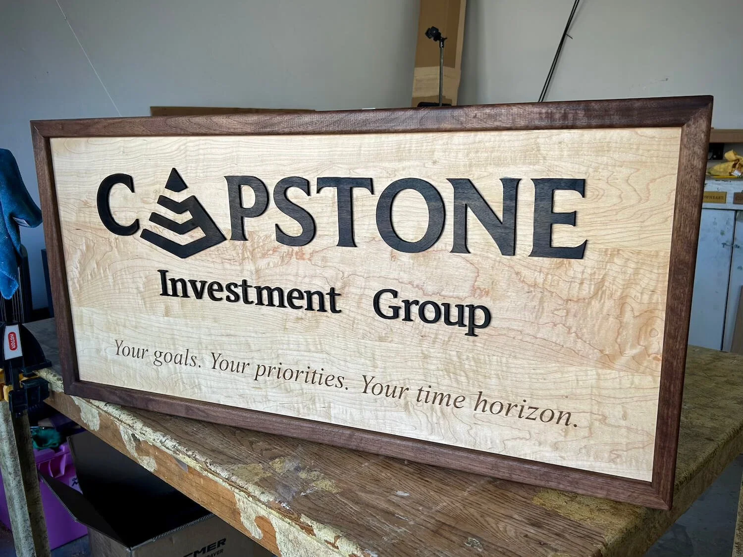 Wooden sign with the logo and name of Capstone Investment Group, and the slogan 'Your goals. Your priorities. Your time horizon.'