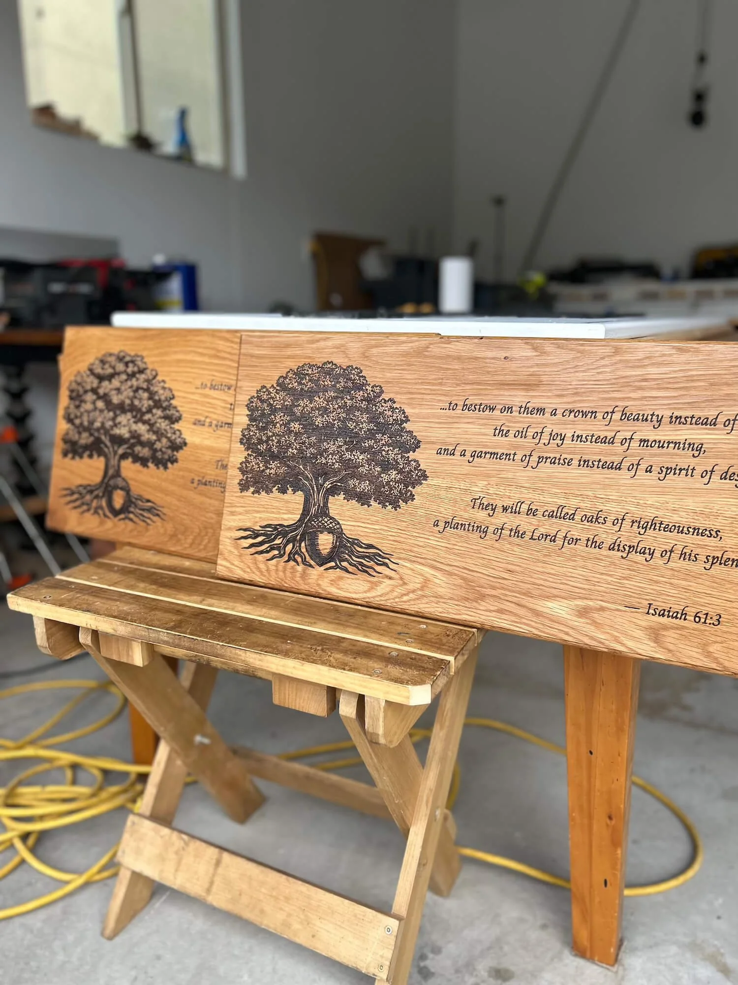 A wooden plaque with engraved text and a tree illustration, resting on a small wooden bench.