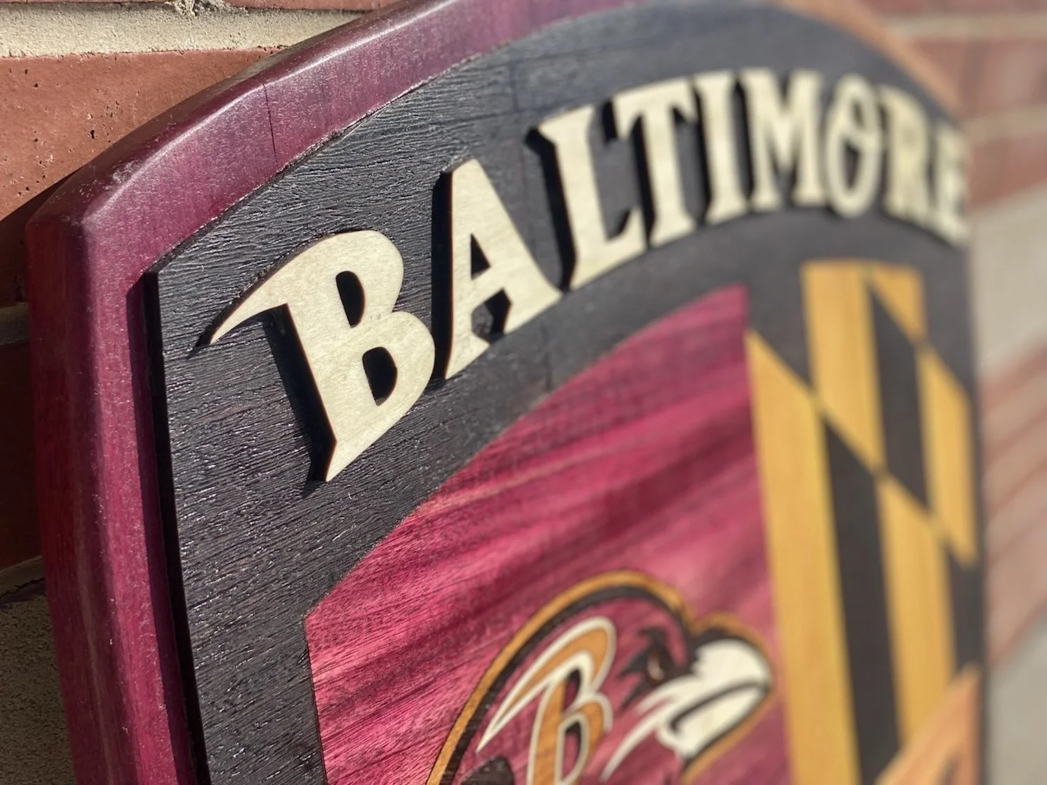 Close-up of a decorative wooden wall sign with the words 'Baltimore' and part of a Baltimore Ravens logo.