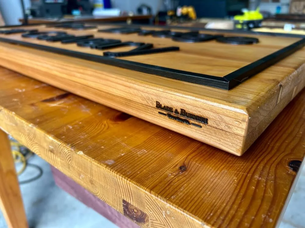 Close up shot of Blade & Burnish logo branded into a cedar wood sign