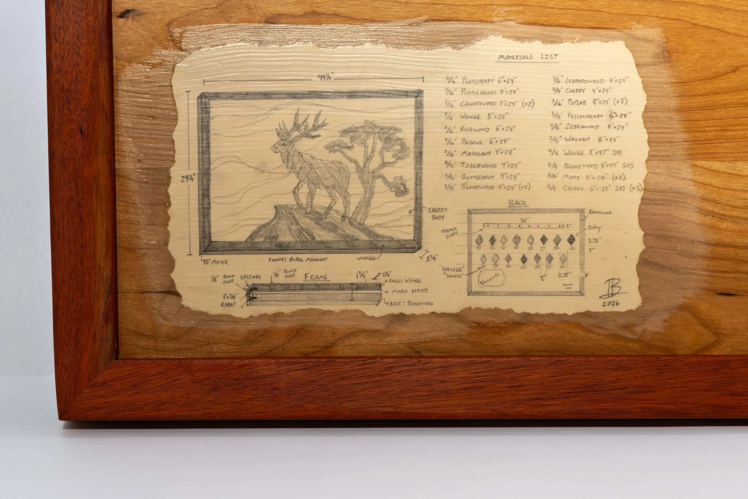 Sketch of a framed artwork of a deer and a tree, with measurements and material list on a piece of paper in a wooden frame.
