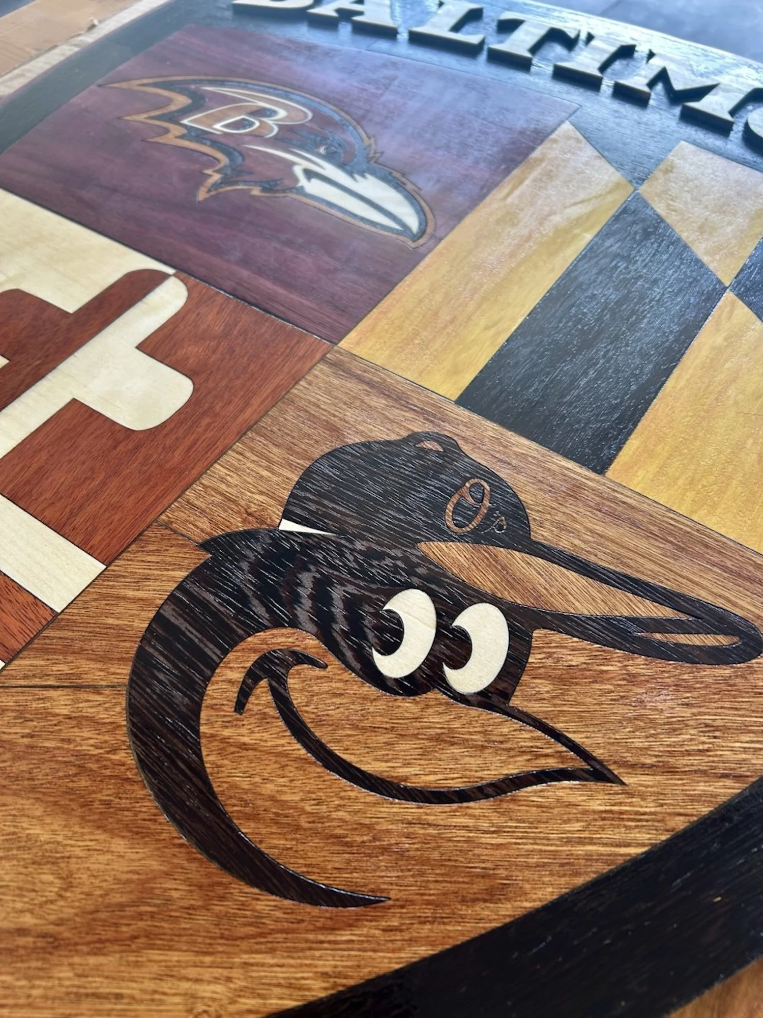 Close-up of a wooden surface with inlayed logos of the Baltimore Ravens and the Baltimore Orioles.