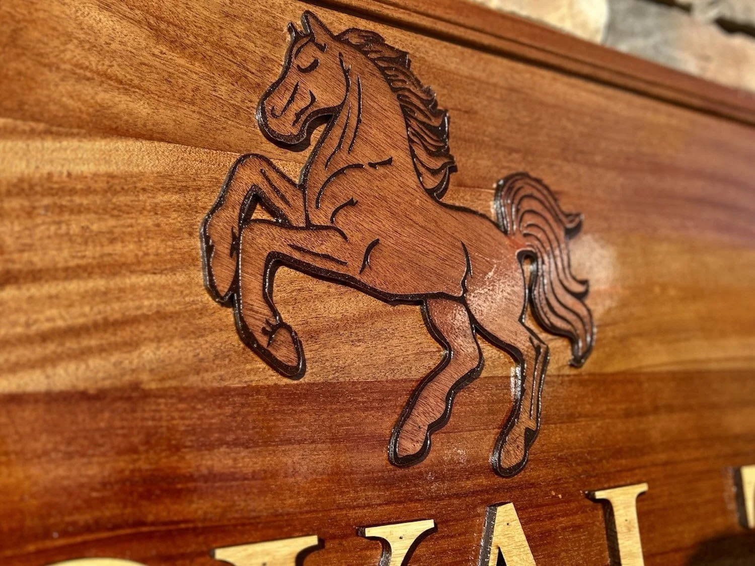 Wooden wall art of a rearing horse with carved and black-outlined details.