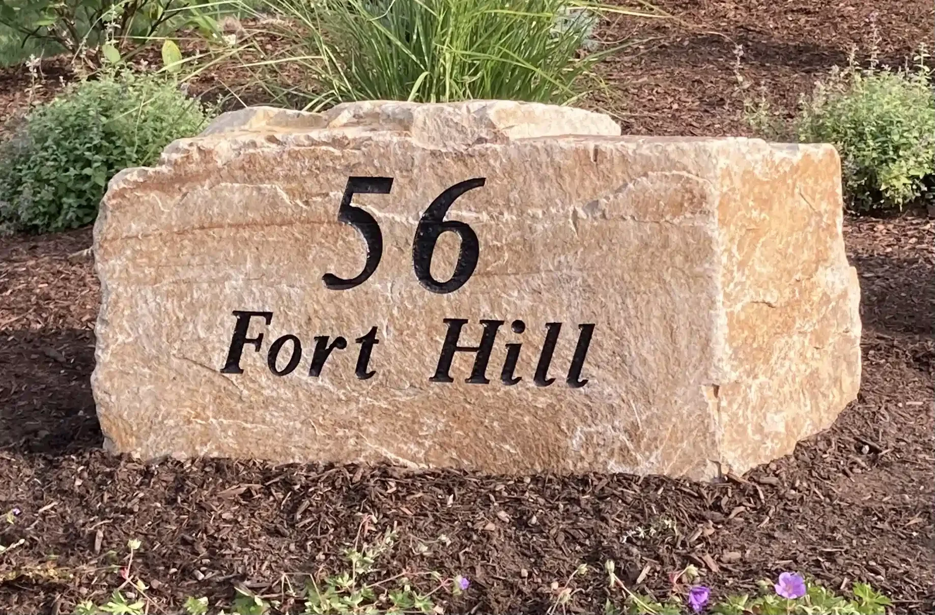 A large beige address stone with black engraved text.