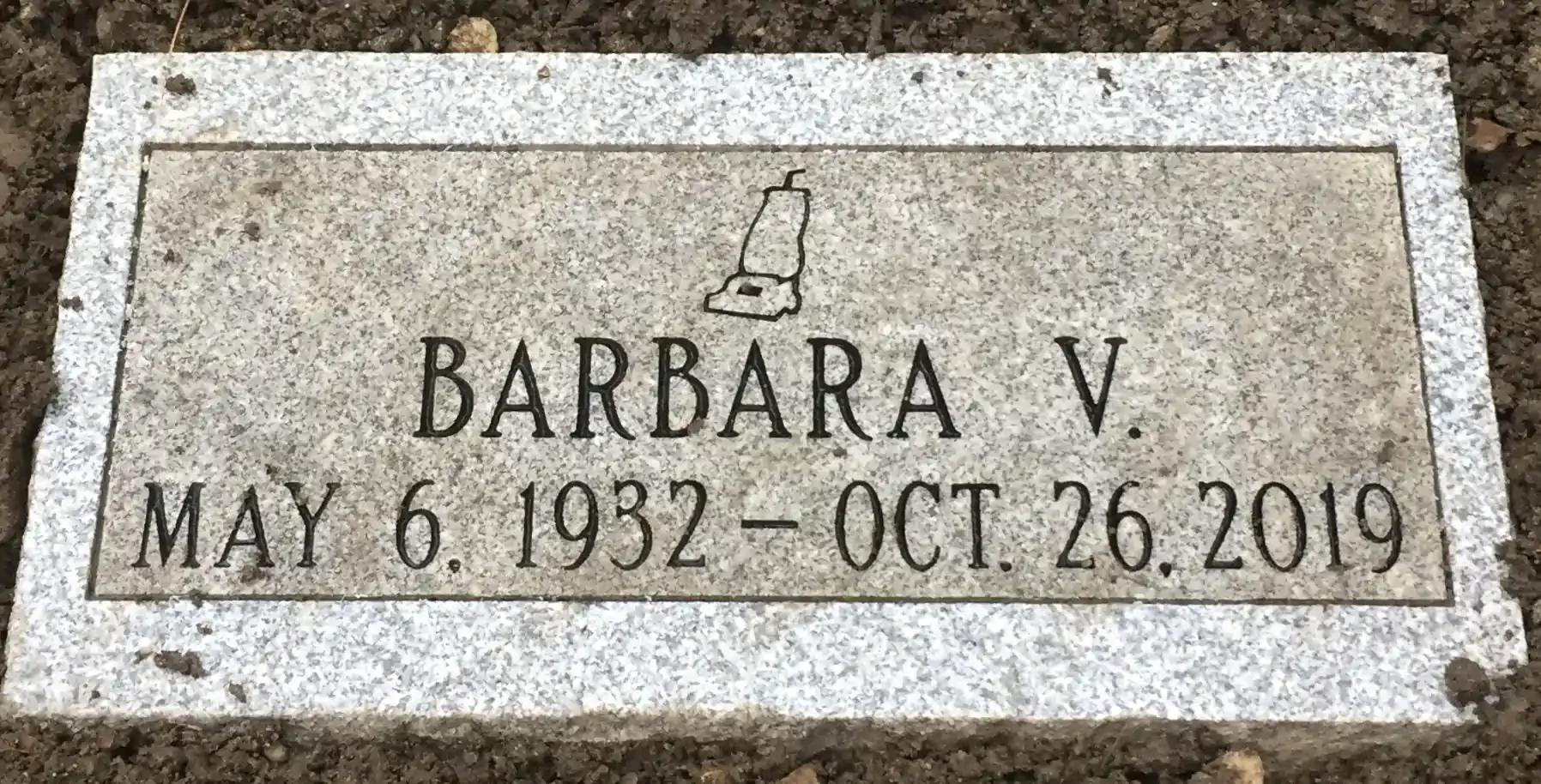 Gravestone with a small illustration of a bottle at the top.