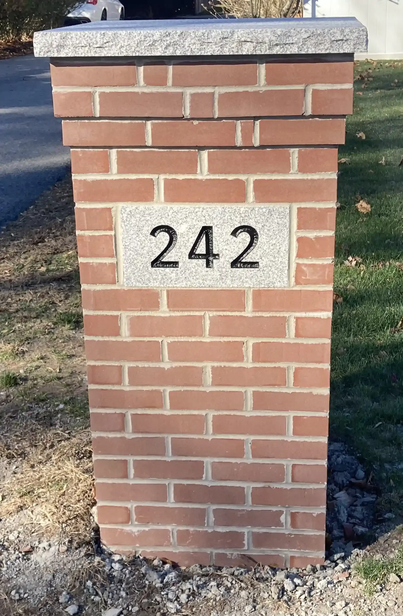 A brick column with the number 242 in black on a gray rectangular stone.
