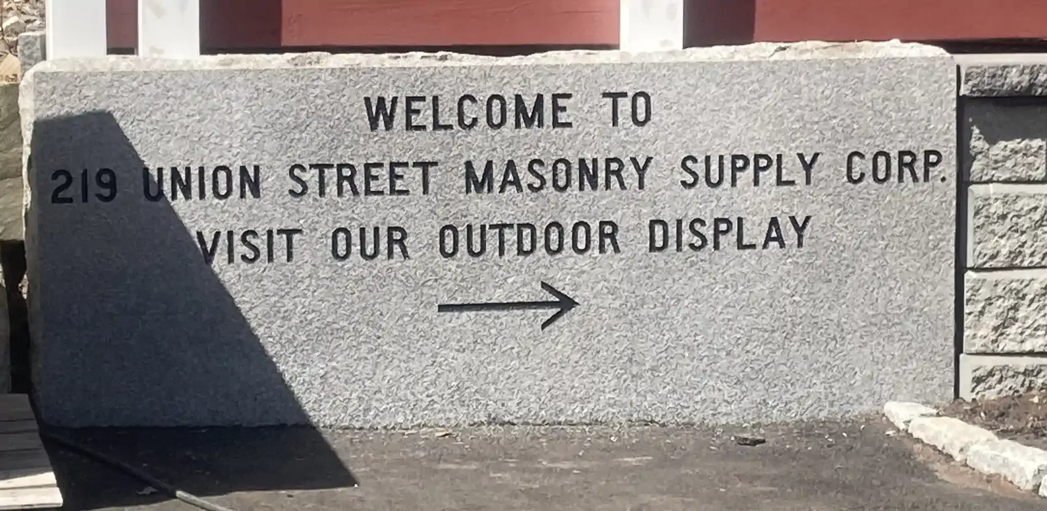 Stone sign reading 'Welcome to 219 Union Street Masonry Supply Corp. Visit our outdoor display' with an arrow pointing to the right.