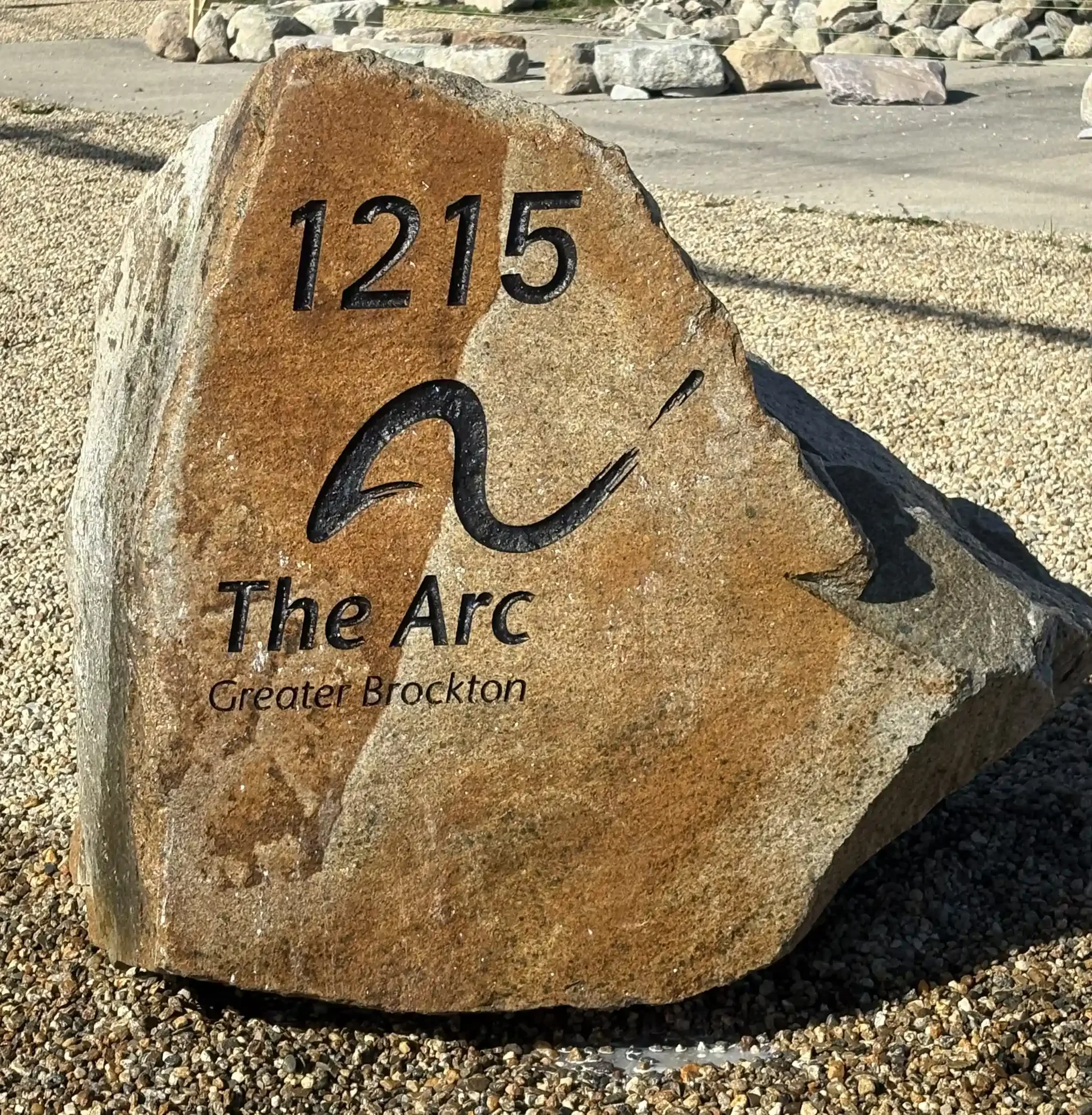 A large address boulder with the house number 1215 engraved on it in black.