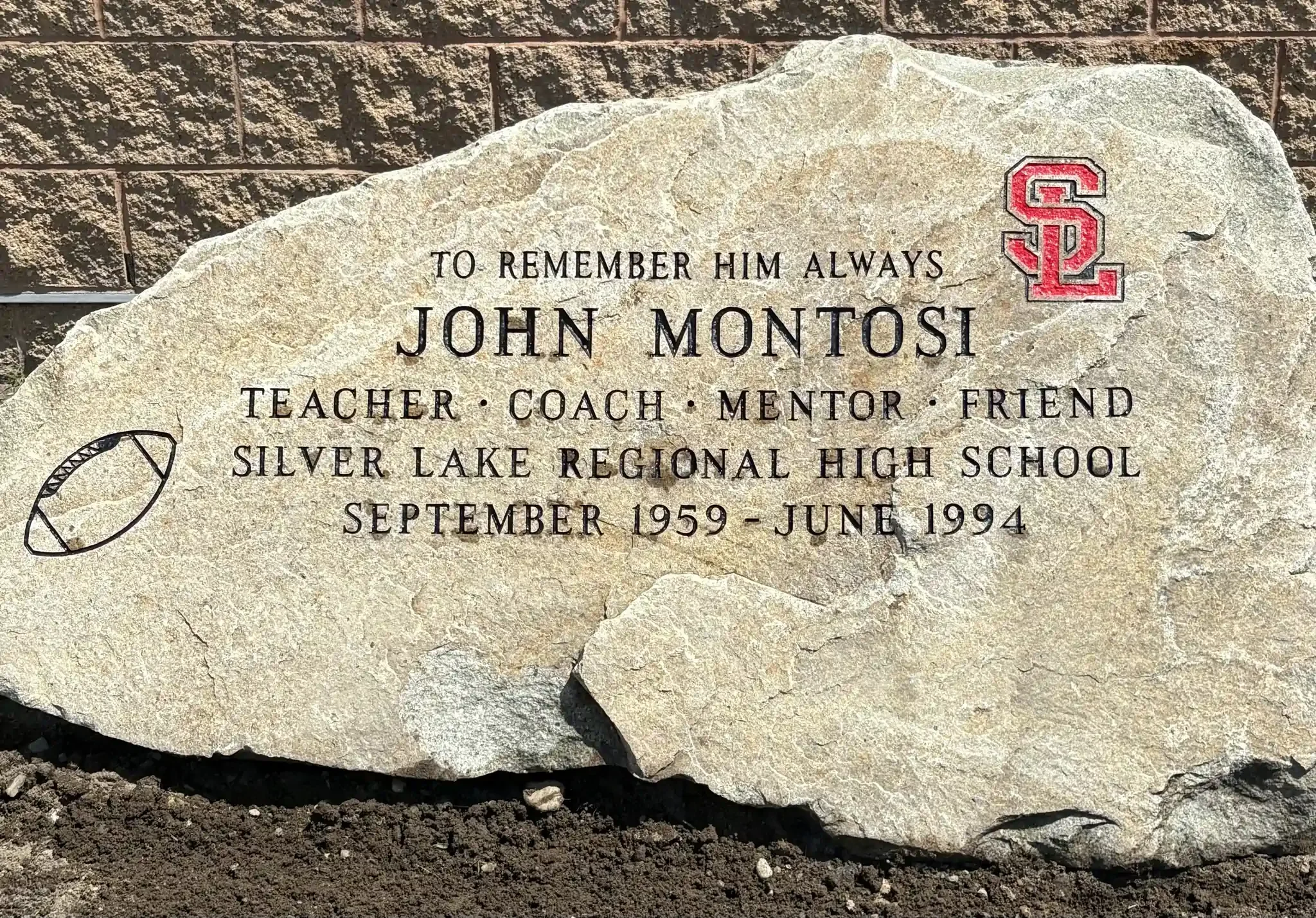 A memorial plaque carved into a large stone with an inscription.