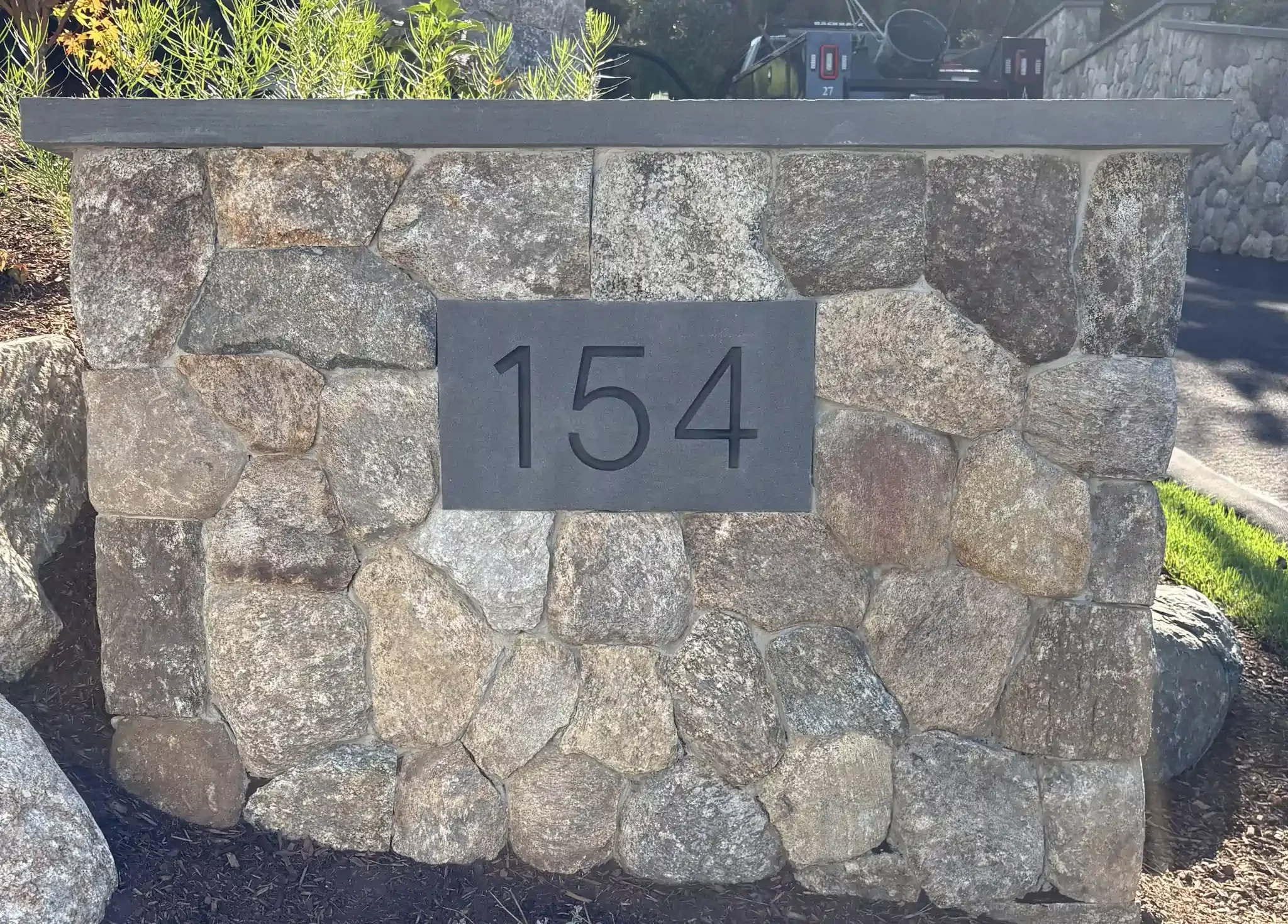 Stone wall showing the house number 154.