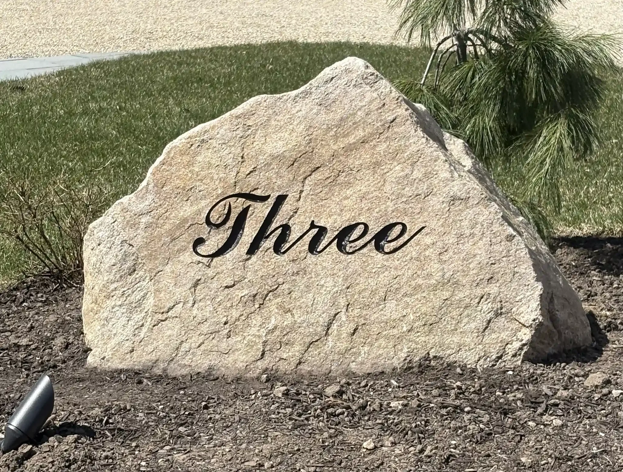 A large beige address stone with engraved black cursive text.
