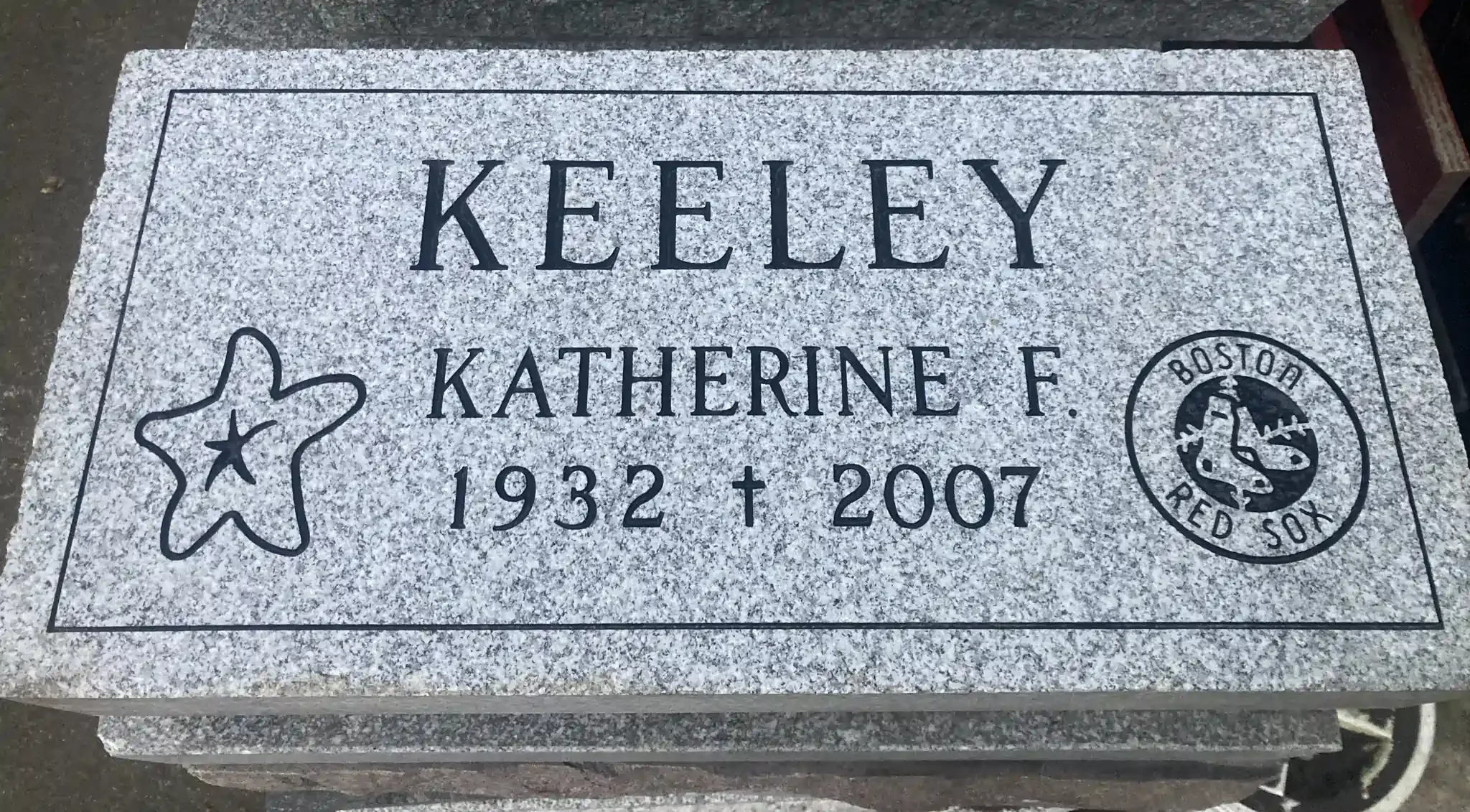 Gravestone with a black outline of a flower, a paw print, and the Boston Red Sox logo.