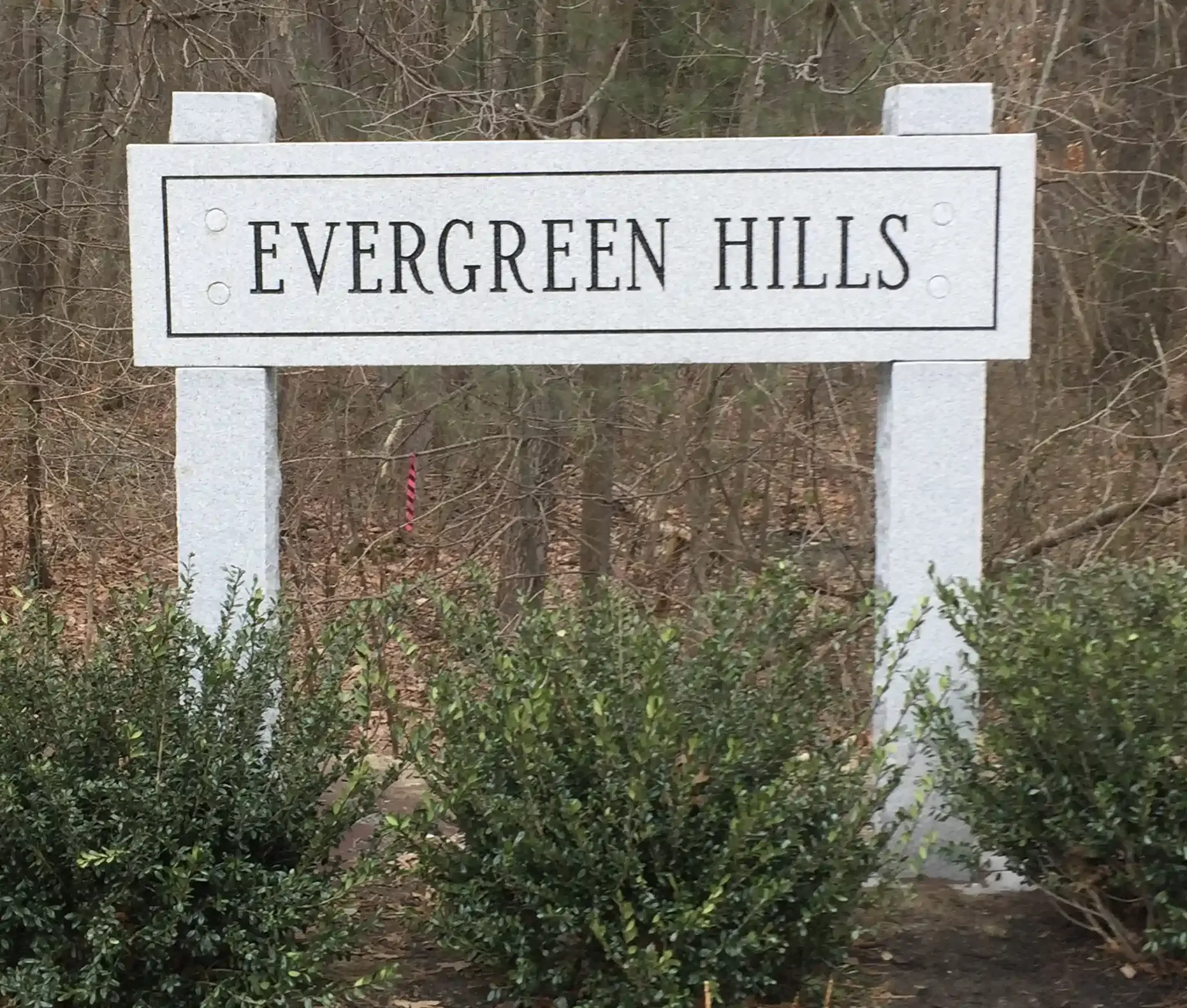 A granite sign with black text that reads 'Evergreen Hills'.