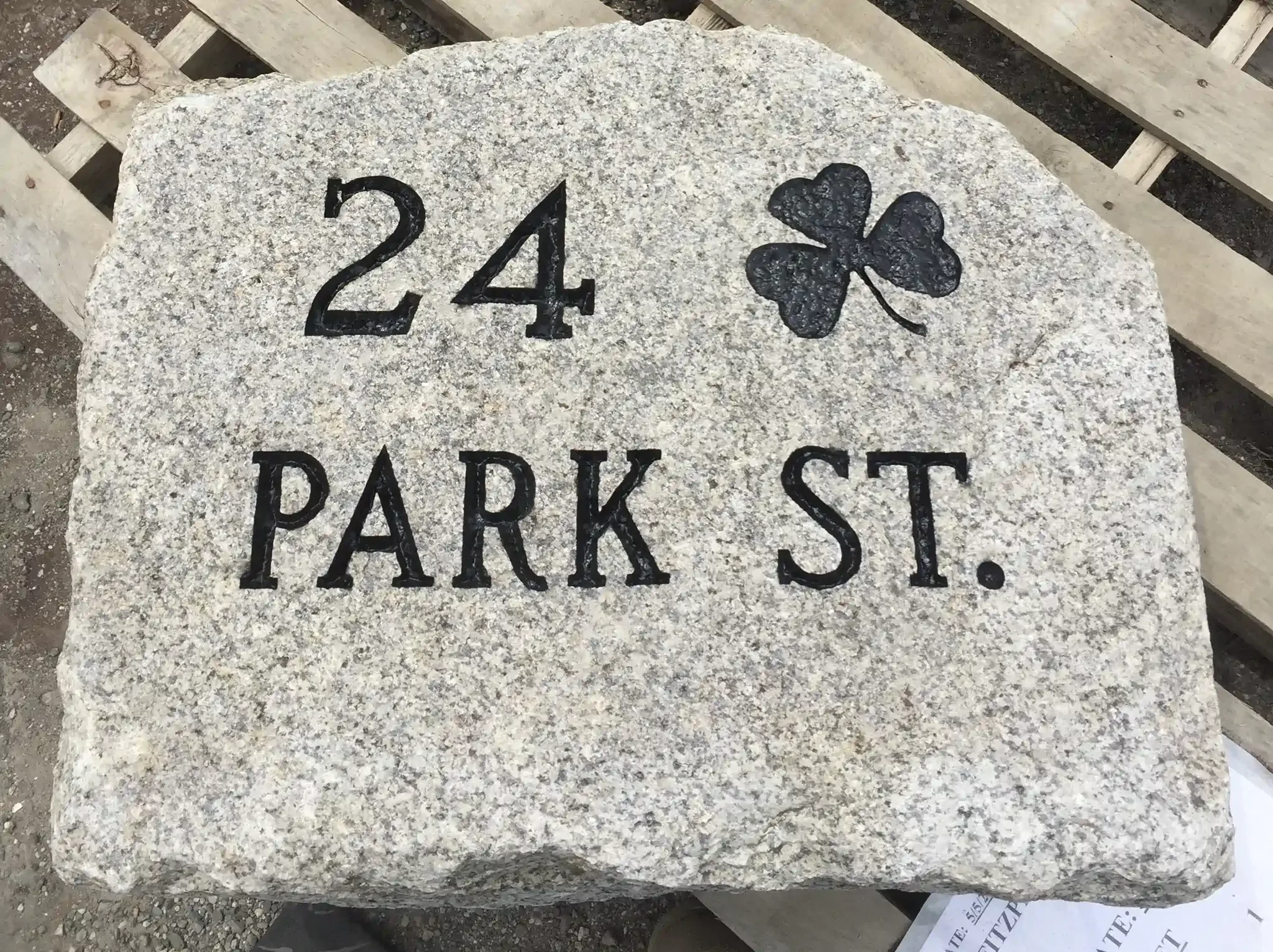 A large granite address stone with the number '24' and a four-leaf clover symbol engraved on it.