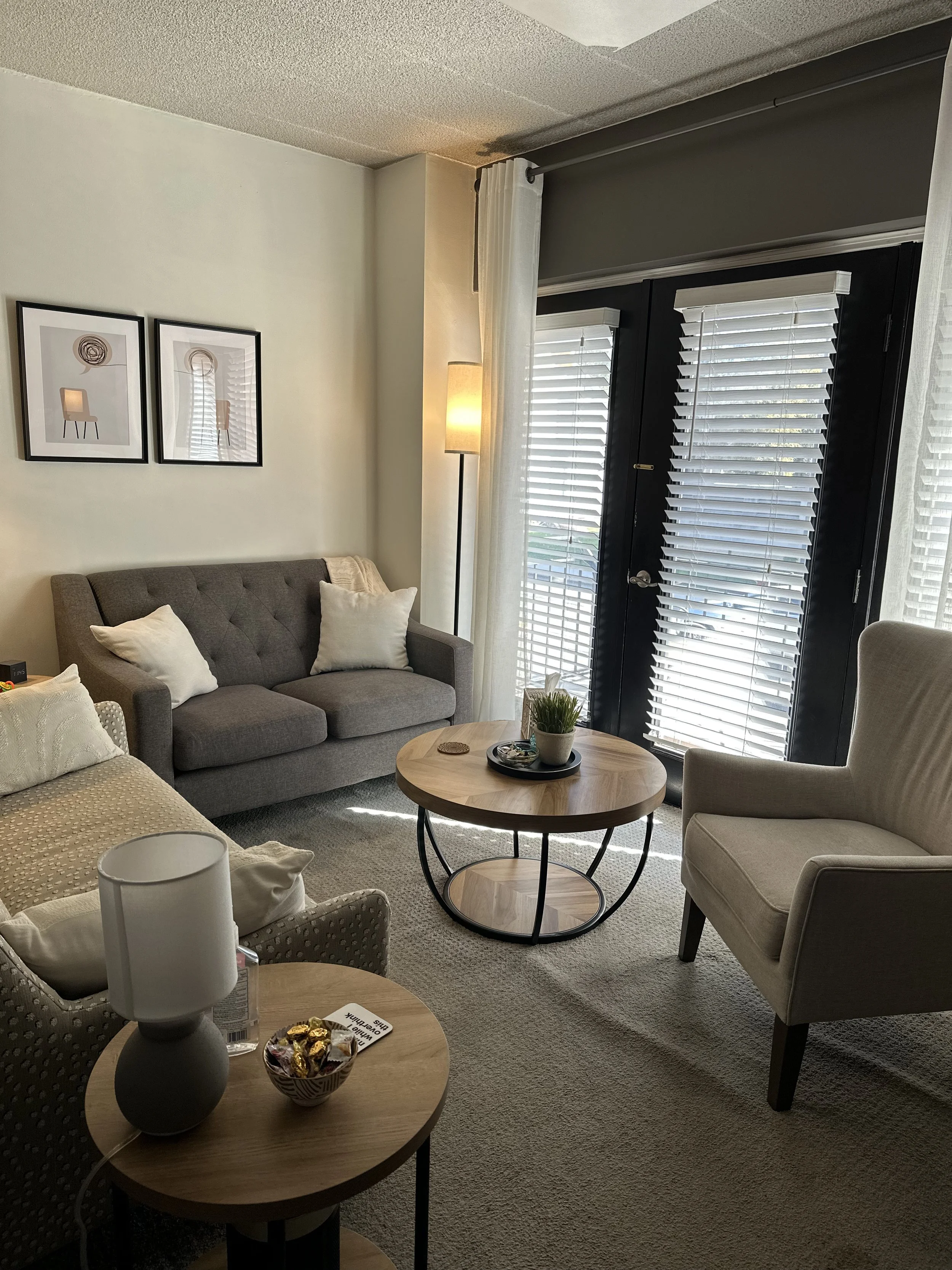 office with two sofas for seating and a single high back chair, a coffee table sits in between and windows invite in natural lighting