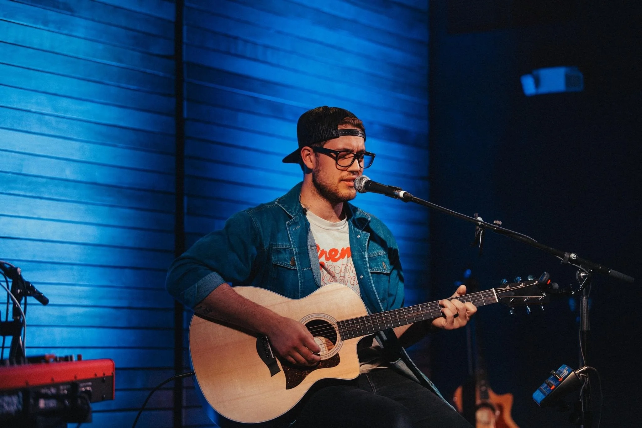 Man playing acoustic guitar and singing into a microphone on stage