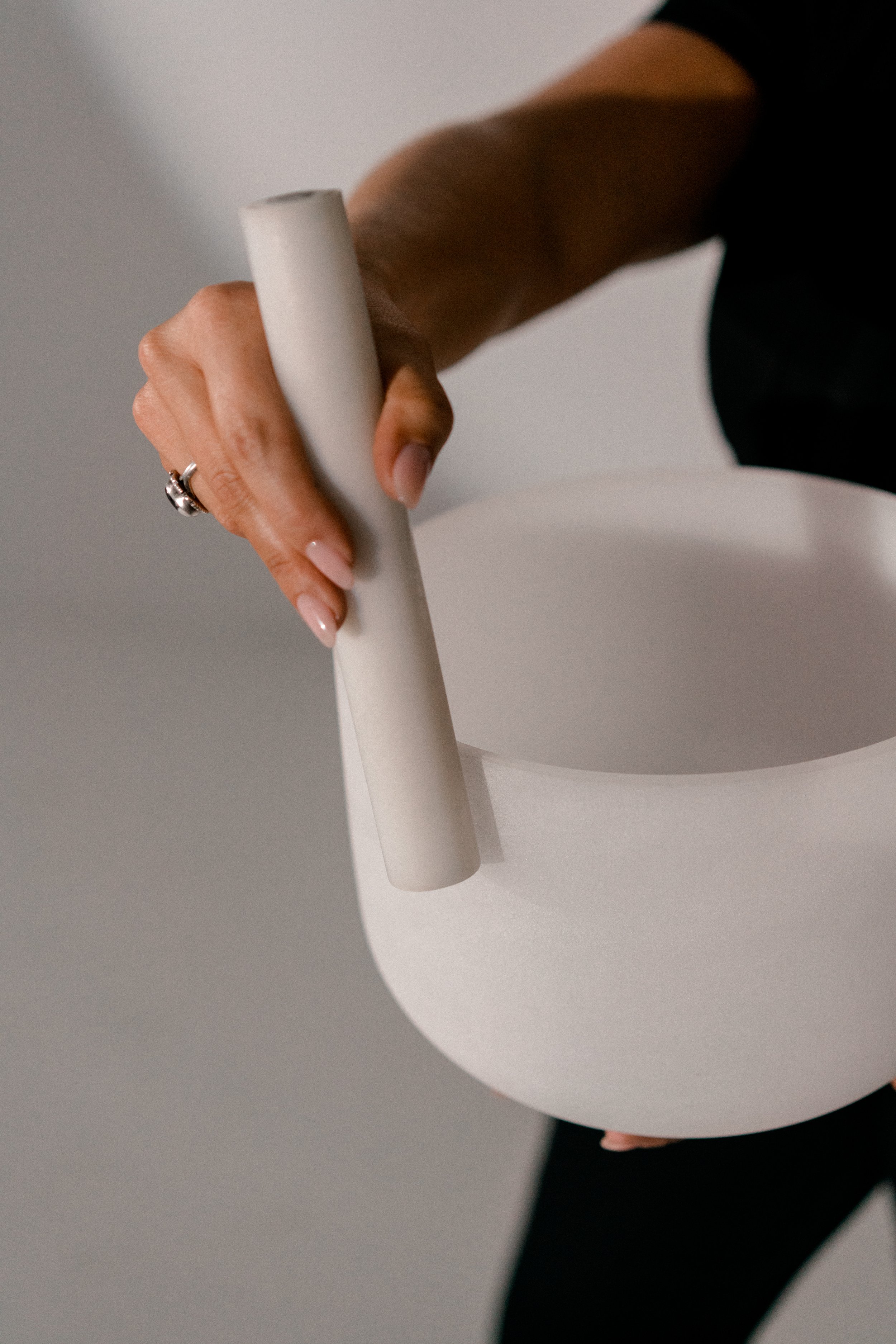 Person holding a blank white cylindrical object and a large white round sheet of paper or poster board.