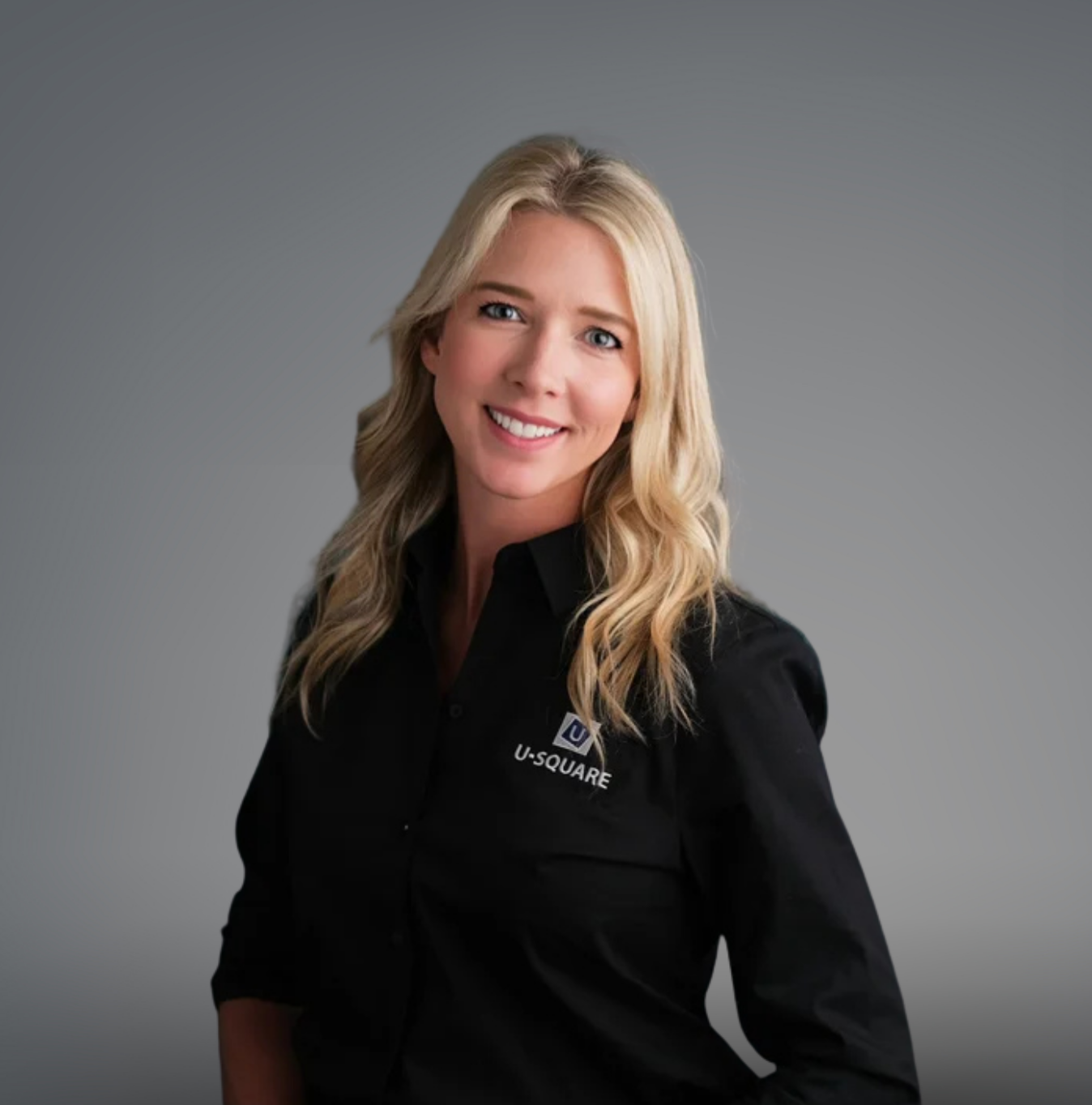 Brooke Moore A woman with blonde hair smiling, wearing a black shirt with the U-SQUARE logo.