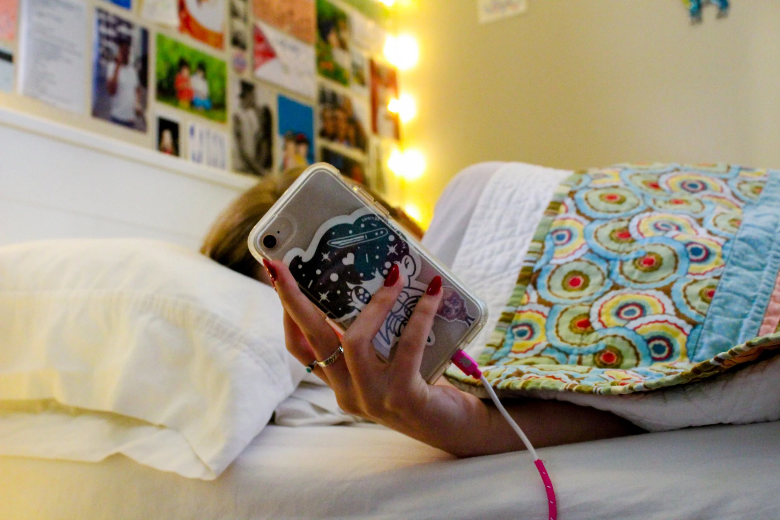 Francesca Dietz, "The Constant Reminder," 2021. Isabella Dietz lays in her bed and checks her BLEND app on her phone. Due to the app being on her phone, school is constantly with her. Technology has lessened the separation students have from school a