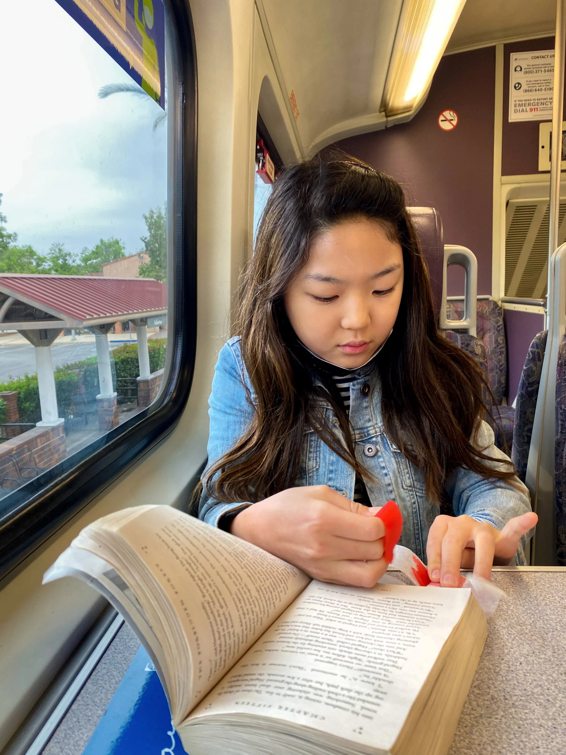 Emily Im, "BookWorm," 2021. My sister is eating gummies while reading a book on the train. She loves books and brings them everywhere she goes. We were going to the beach for Mother's Day. Her favorite book is "Harry Potter and the Chamber of Secrets