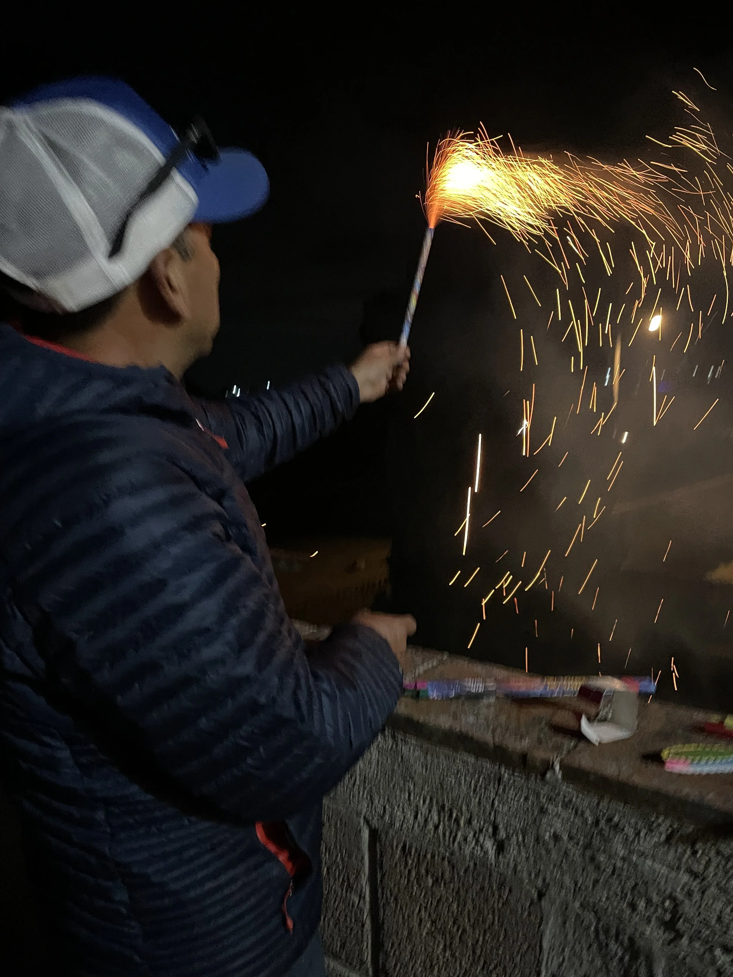 Eveline Baez Tzompa, "The spark comes back," 2024. This is a picture of my dad lighting up some fireworks on Christmas. This was the only Christmas that our family was split apart. A few months before this, he left for Mexico; he saved up money and d