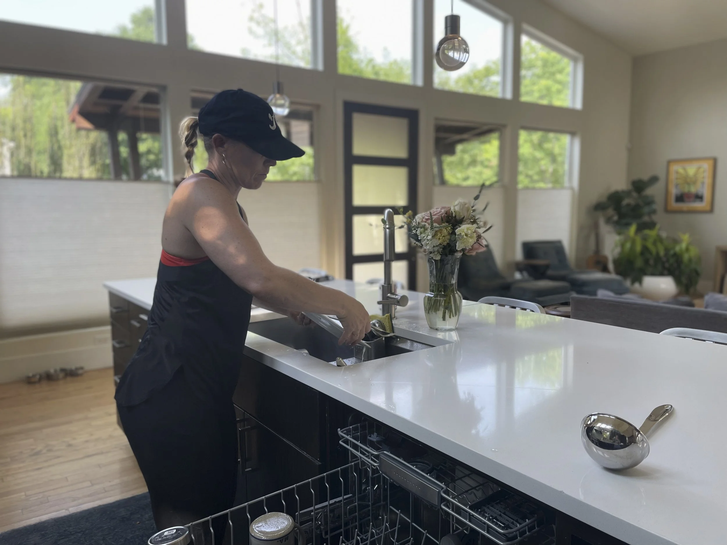 Harper Bergeron, "Housework," 2022.
My mom comes home from her job just to be followed by more responsibilities. Here she is, doing the dishes, still wearing what she trained in all day. The sun is setting on her, and there is still more to do. A har