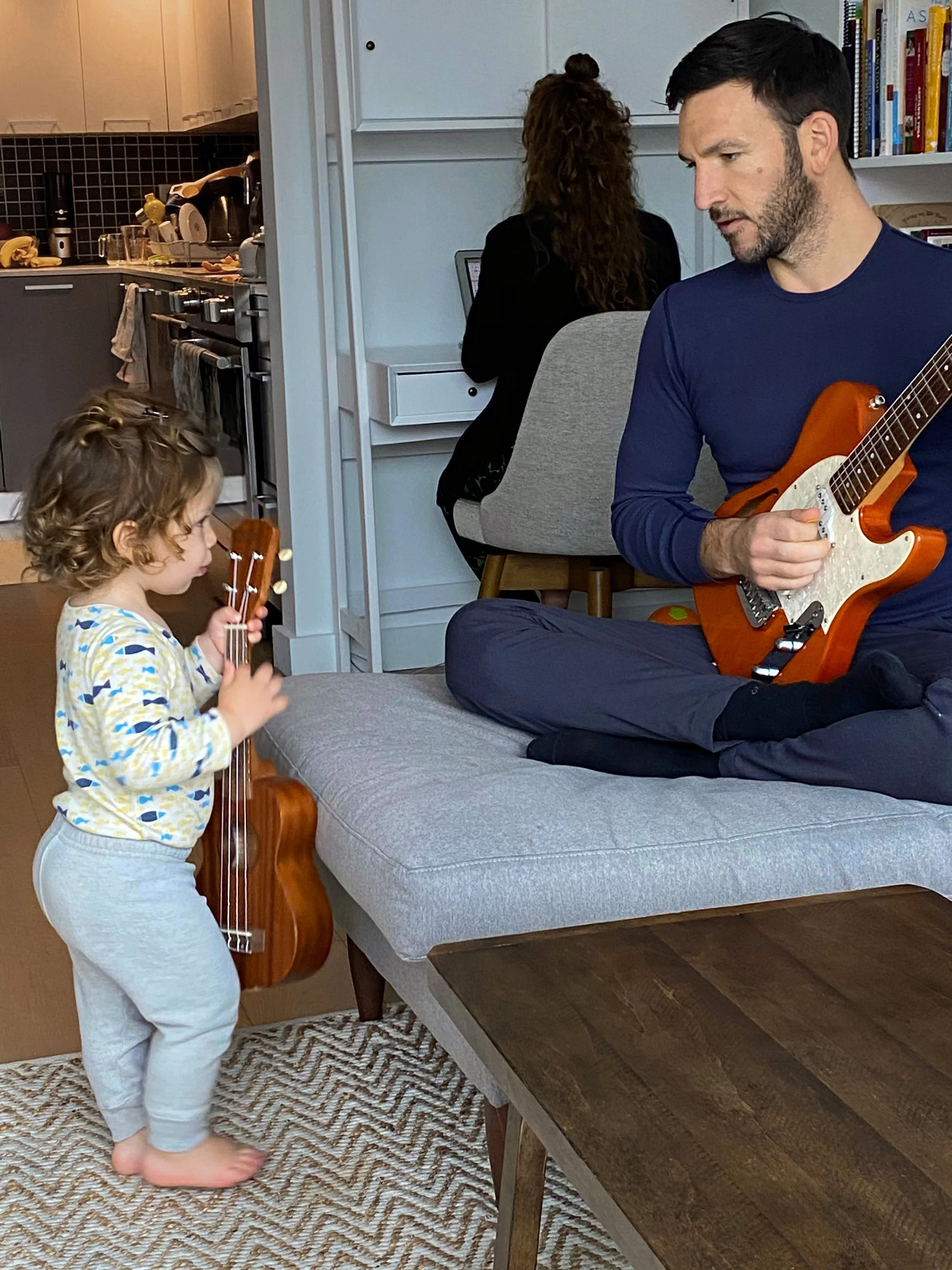 Cam Magnano, "Guitar Players," 2020. "In the photo, you can see my brother, dad, and stepmom all doing some type of work. My dad plays guitar for my brother while also practicing for his job. My stepmom is in the back doing some work on her laptop, a