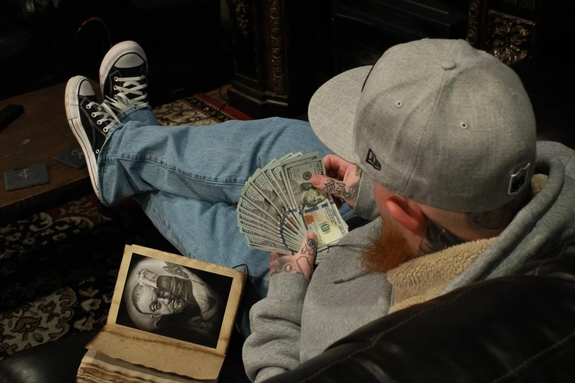 Aiden Yarnal, "Session Done," 2024. This is a picture of my dad counting up his money from finishing a tattoo session. The book to his left is his custom-made portfolio by a woman in Switzerland.