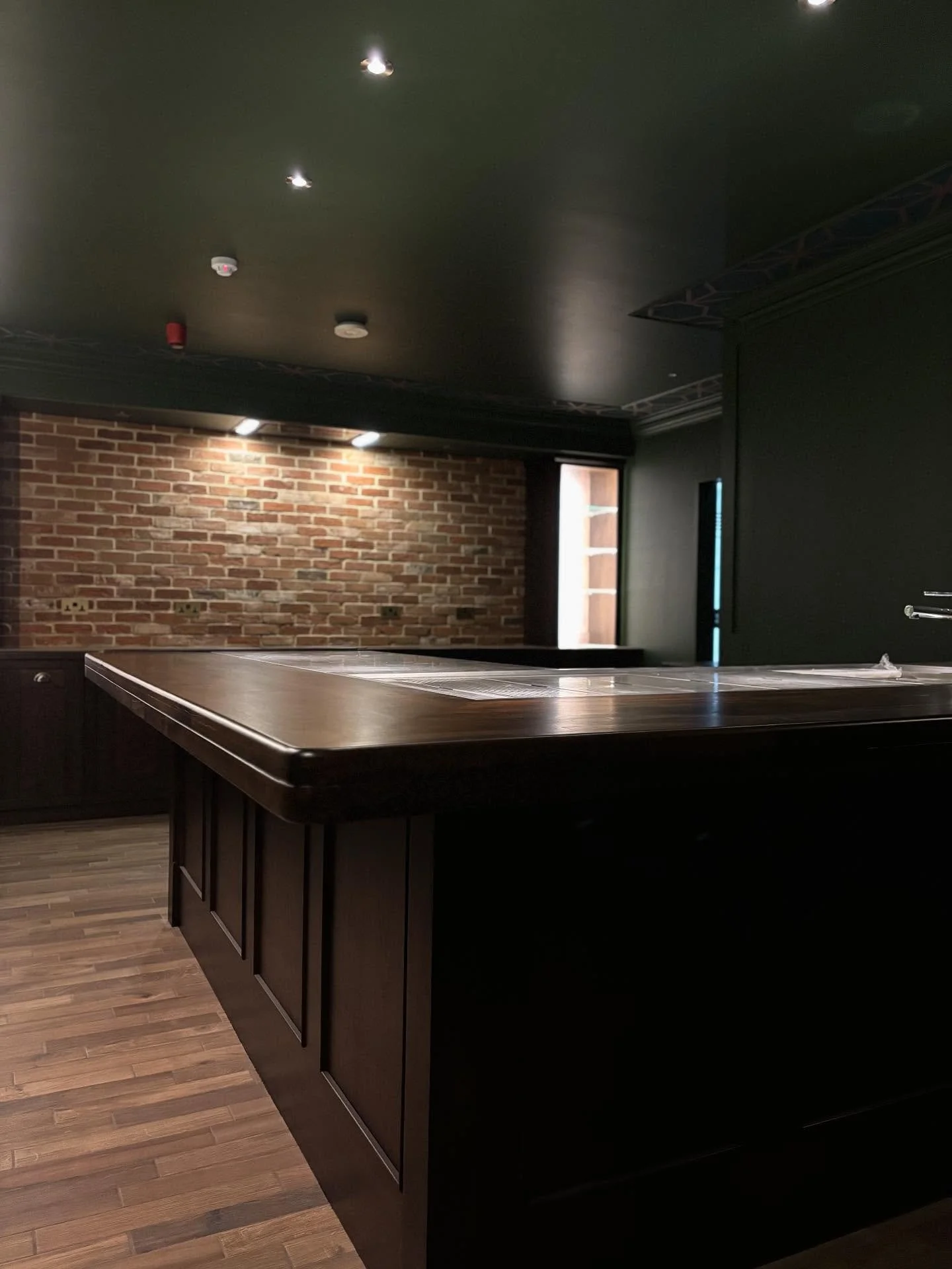 Step through the hidden door and discover a space where craftsmanship meets intrigue.
Solid walnut worktops, rich paneling, and exposed brick come together to create a timeless speakeasy atmosphere &mdash; refined, warm, and full of character.

A bar